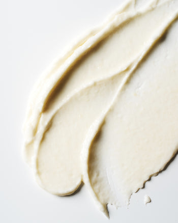 A close-up of a thick, creamy off-white haircare product swatch, showing its smooth texture and rich consistency on a clean white background.