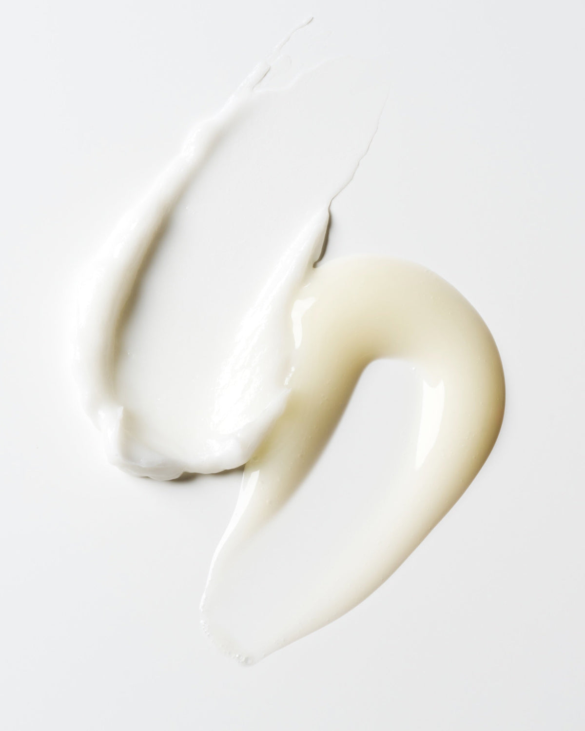 Two hair product smears, one a  thick, creamy off-white, the other a smooth glossy off-white texture 