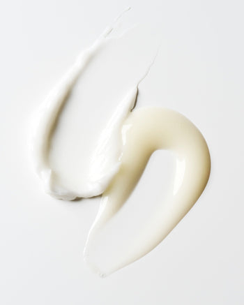 Two hair product smears, one a  thick, creamy off-white, the other a smooth glossy off-white texture 